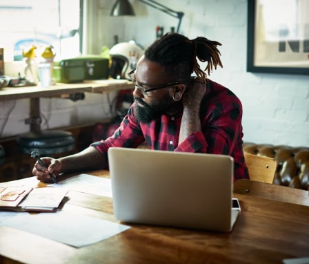 Man sketching at desk in front of laptop