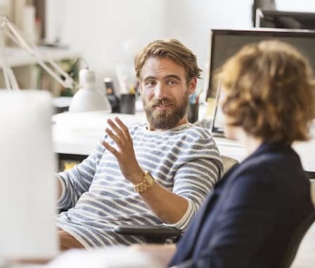 Two colleagues talking at a computer desk