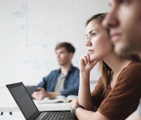 Students listening in class, taking notes on laptops