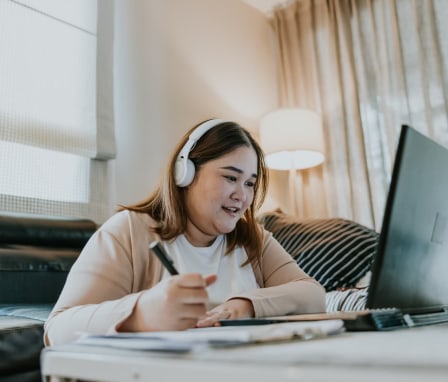 Woman taking notes from laptop at home